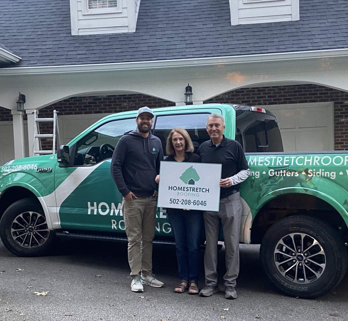 Homestretch Roofing team with homeowners and branded truck